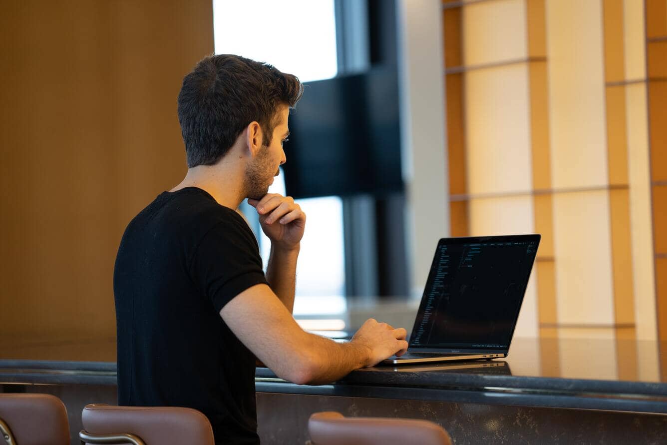 Usuário homem sentado em frente ao computador analisando se há risco em atualizar a versão do WordPress