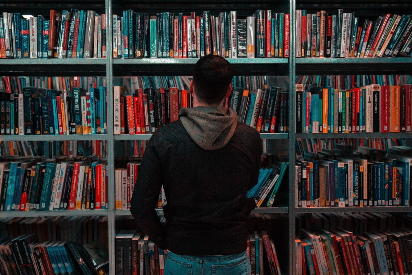 Homem olhando para estante de livros representando como aumentar o limite de memória WordPress